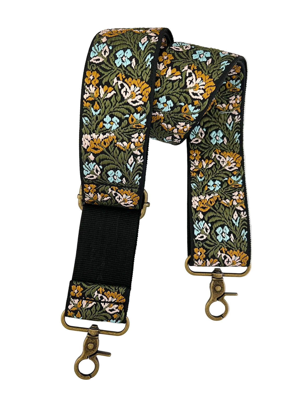 A floral patterned fabric shoulder strap with brass-colored metal hardware, laid flat on a white background.